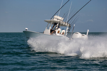 Center console fishing boat turning hard and throwing spray.