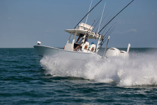 Center console fishing boat turning hard and throwing spray. - Powered by Adobe