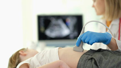 Doctor gastroenterologist making ultrasound examination of liver and pancreas to child in clinic closeup. Diagnosis and treatment of diseases of internal organs in children concept - obrazy, fototapety, plakaty