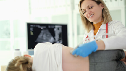 Doctor pediatrician conducting ultrasound examination of kidneys of child in clinic. Instrumental...