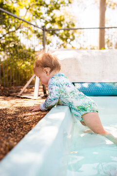 Baby standing on step in backyard swimming pool unsupervised