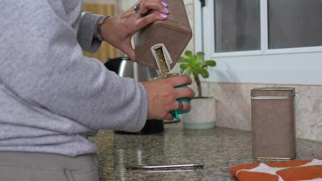 Woman preparing mate in the kitchen, a south american traditional drink.