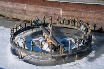 equipment with pipes and taps with illumination in an empty fountain in winter with frozen water