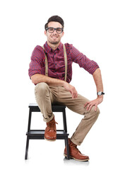 Nerdy man, smile for portrait while sitting on a chair and wearing hipster clothing with glasses....