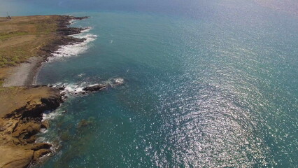 Breathtaking aerial slow motion view from above of blue ocean and waves crashing on rocks.