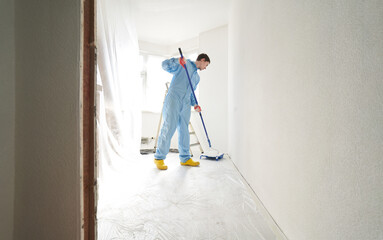 Man dipping a roller into a palette of paint.