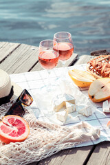 Romantic sunset dinner on the beach. Table honeymoon set for two with luxurious food, glasses of rose wine drinks in a restaurant with sea view. Summer love, romance date on vacation concept.   