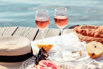 Romantic sunset dinner on the beach. Table honeymoon set for two with luxurious food, glasses of rose wine drinks in a restaurant with sea view. Summer love, romance date on vacation concept.   