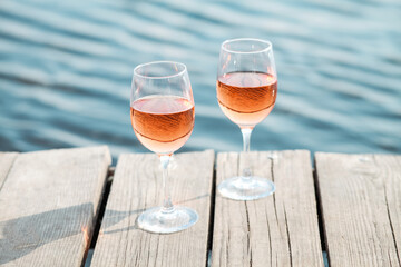 Romantic sunset dinner on the beach. Table honeymoon set for two with luxurious food, glasses of rose wine drinks in a restaurant with sea view. Summer love, romance date on vacation concept.   