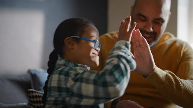 Multiracial boy with Down syndrome high fiving father