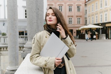 Fototapeta premium Young successful caucasian woman outside working remotely, having a business call