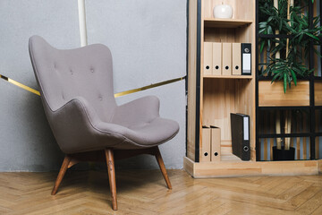Gray chair upholstered with textiles with wooden legs in a modern office interior. Living room or office interior. Details of modern design.