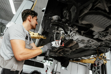 Auto mechanic repairs running gear of a car in car service