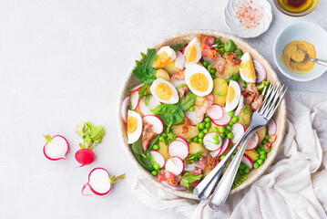 Summer fast balanced salad with baby potatoes, fried bacon, radishes, farmer organic  eggs and green peas and herbs, seasoned with olive oil, mustard sauce, balsamic and lemon.  Spring balanced diet