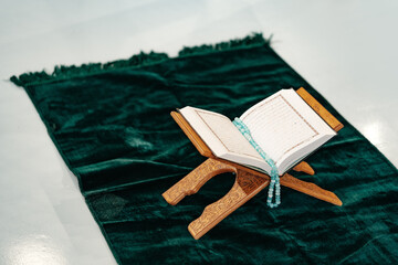 Holy Quran with prayer rosary beads on wooden stand
