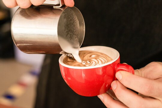 barista pouring the milk into a flat white coffee