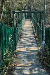 A narrow footbridge leads across a river inviting speculation whoever crosses will enter a new and interesting world