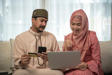 Islam beautiful adult couple at home relaxing on couch shopping online.