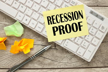 Recession proof text on yellow sticky note and work desk with white keyboard
