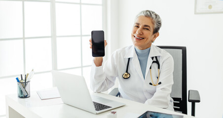 Experienced doctor recommending a smartphone while sitting in her office