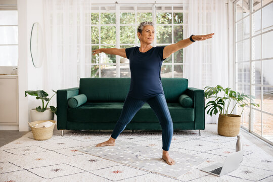 Warrior pose for seniors: Mature woman shows her strength and flexibility as she practices this yoga pose at home