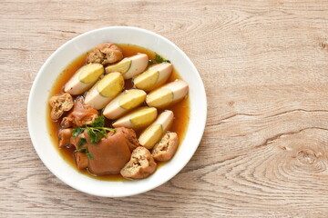 boiled half cut egg with tofu in herb brown soup and pork leg on plate 