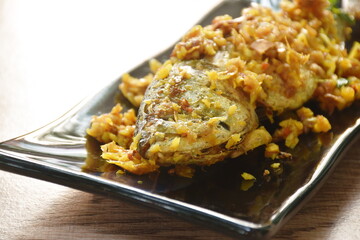 deep fried mackerel fish with turmeric dressing chili and garlic on plate in white background