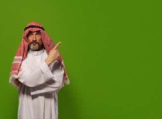 mature Muslim man in a traditional dishdasha points his finger towards copy space symbolizing concept of Sharia law, the Islamic legal system based on teachings of Quran and Hadith. authority