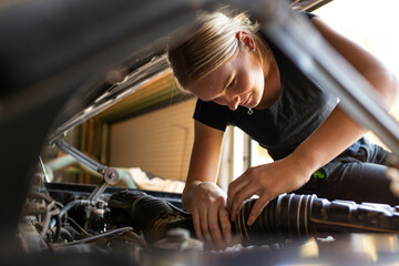young australian tradesperson mechanic fixing car engine in automotive repair garage