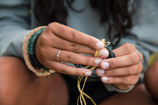 Close-up of an Aboriginal girl's hands as she is preparing threads for weaving baskets and bracelets