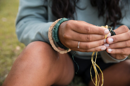 Close up of an Aboriginal girl, weaving threads to make bangles and bracelets