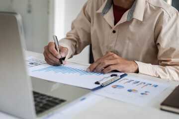 Businessman pointing at financial chart document and statistical market growth analysis. Accounting concepts and financial planning for investment.