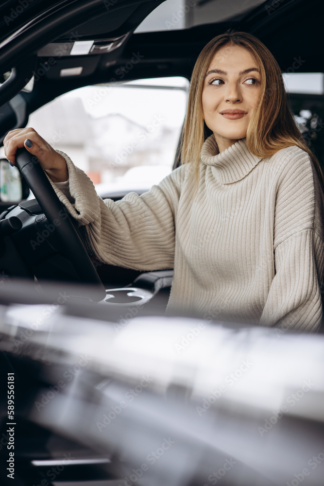 Wall mural young woman sitting in car in a car showroom