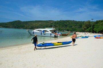 Two people carrying a canoe at the beach