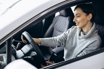 Young woman sitting in car in a car showroom