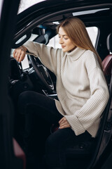 Young woman sitting in car in a car showroom