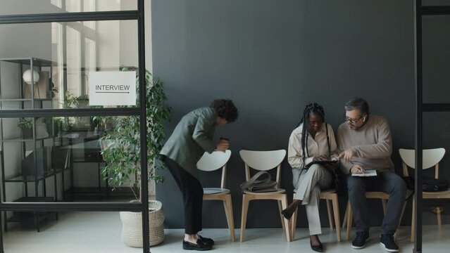 Timelapse of black and Caucasian men and women sitting in line, holding CVs, writing, coming, leaving, waiting for interview