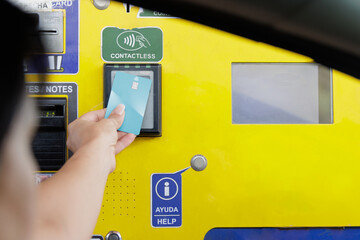 Woman's arm paying with a bank card a highway toll at an ATM through the car window