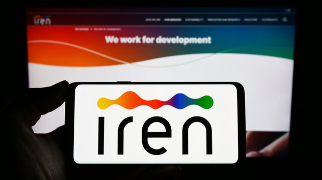Stuttgart, Germany - 03-31-2023: Person holding smartphone with logo of Italian utility company Iren S.p.A. on screen in front of website. Focus on phone display.