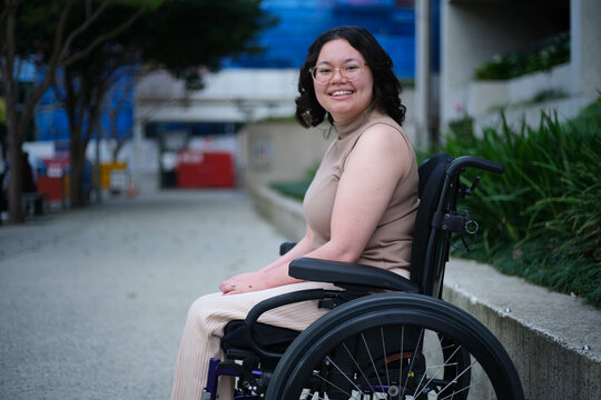 Smiling Filipina woman in wheelchair outside