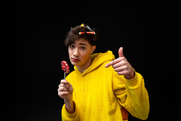 A young guy addicted to sweets, candies and sugar. Isolated on black background. copy space.