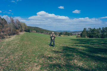 Modern army soldiers using aerial drone for artillery guidance and scouting view enemy positions in military operation.