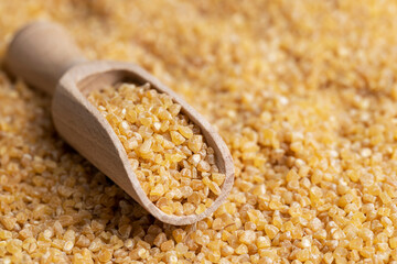 Not cooked wheat porridge with a wooden spoon