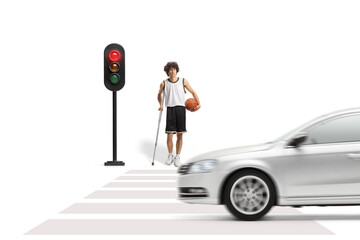 Basketball player with a crutch waiting at a traffic light to cross a road