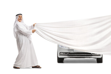 Arab man in traditional disdasha holding a white piece of cloth in front of a car
