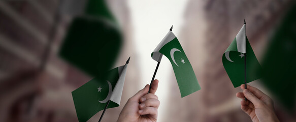 A group of people holding small flags of the Pakistan in their hands