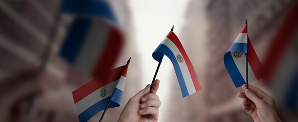 A group of people holding small flags of the Paraguay in their hands - obrazy, fototapety, plakaty