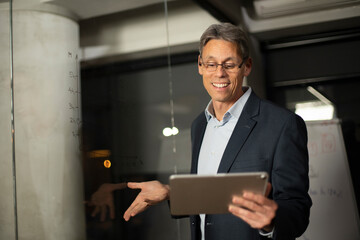 Portrait of successful businessman in office. Man writing on the glass board in office.