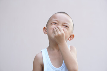 Asian boy covering his nose from the bad smell with his hand