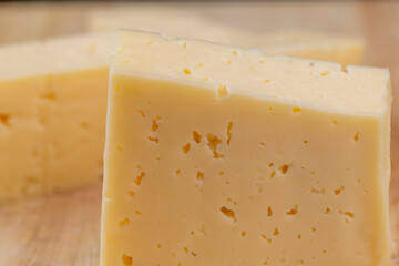 Hard cheese with holes cut into thick pieces on a cutting board